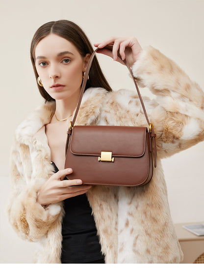 Model in faux fur jacket holding caramel leather shoulder bag by the strap