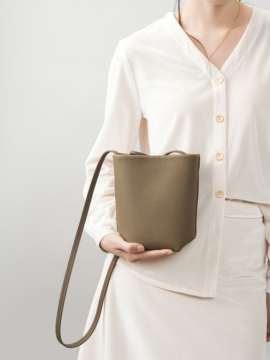 Model holding elephant gray bucket bag showing front view and strap detail