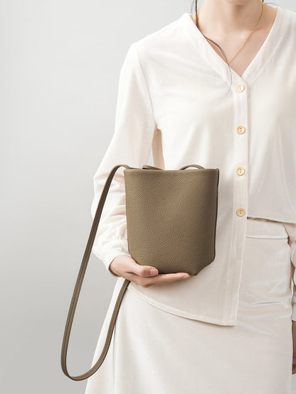 Model holding elephant gray bucket bag showing front view and strap detail