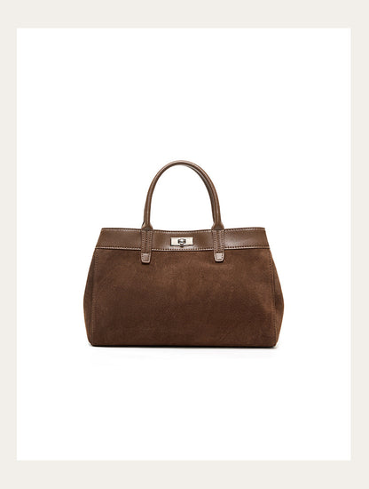 Front view of a brown suede cowhide bag with smooth trim and top handles