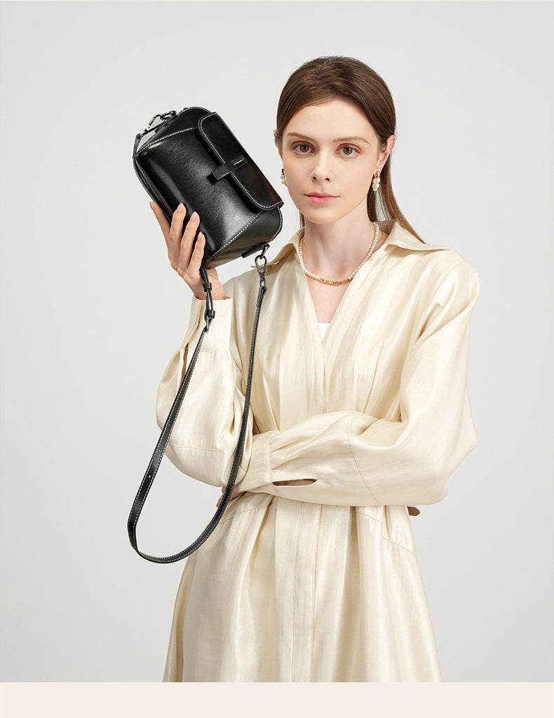 Model holding a black leather crossbody bag with silver-tone hardware