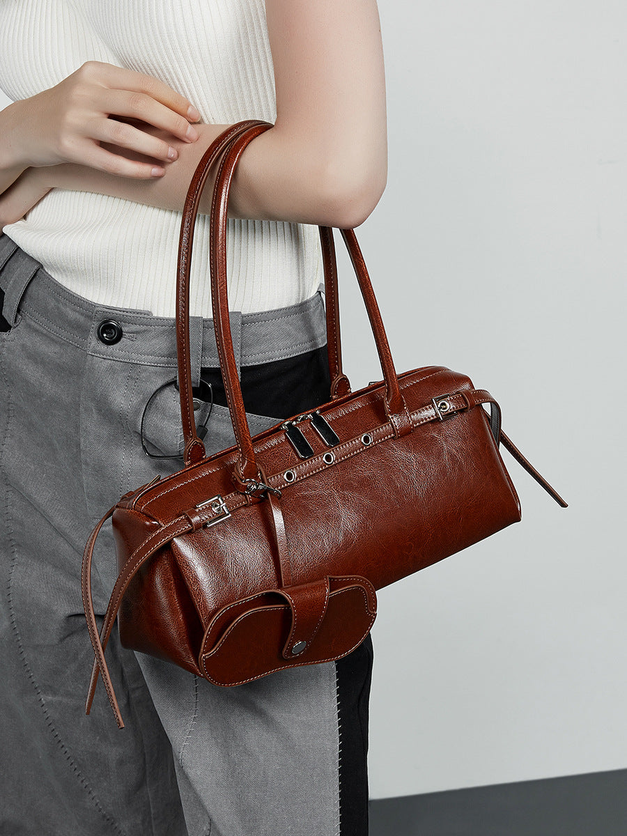 Close-up of brown leather barrel bag carried at the side