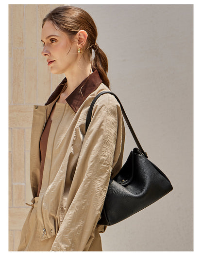 Three-quarter view of a model in beige carrying a black pebbled cowhide crossbody bag