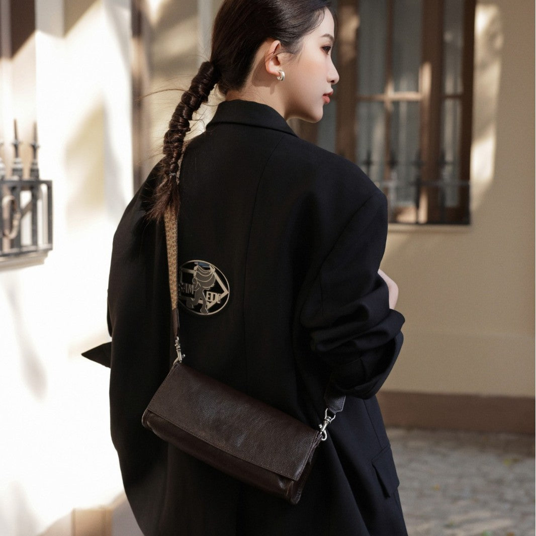 Coffee leather flap bag carried crossbody from the back