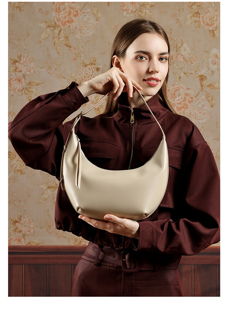 Model holding beige crescent bag in front