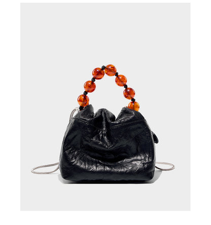Front view of black crinkle bag with amber bead handle and chain strap