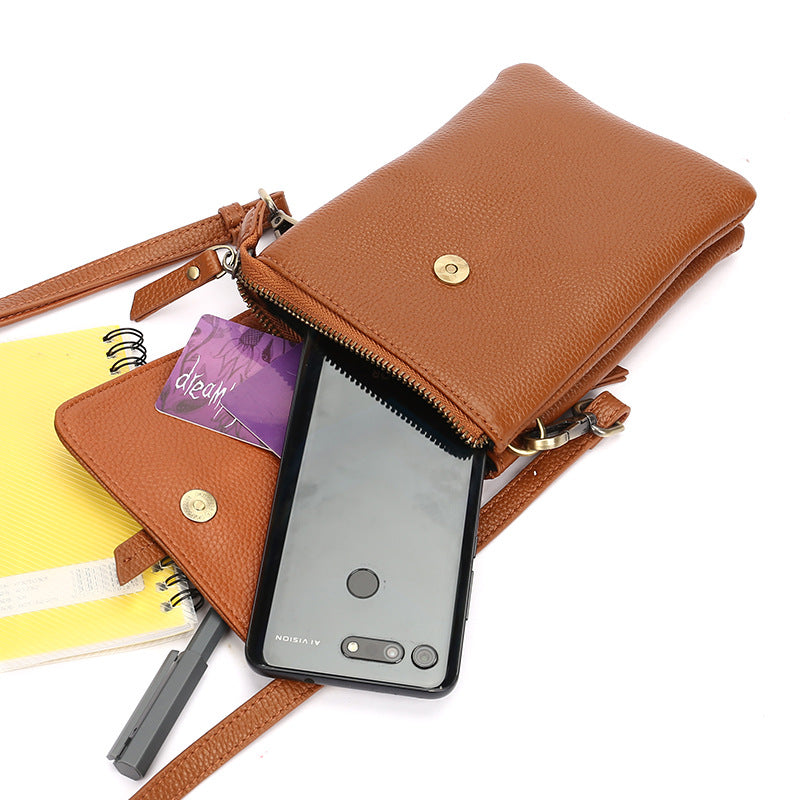 Caramel leather phone bag styled with phone, notebook, and pen