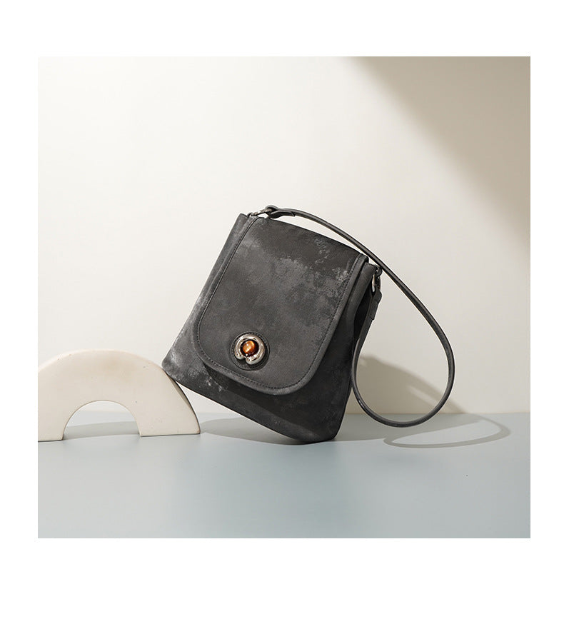 Pewter gray split leather bucket bag angled side view on table