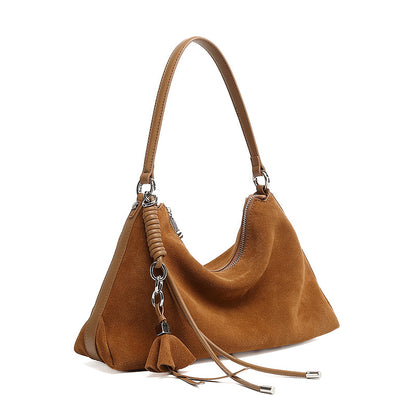 Brown nubuck cowhide underarm tote bag with tassel detail on white background