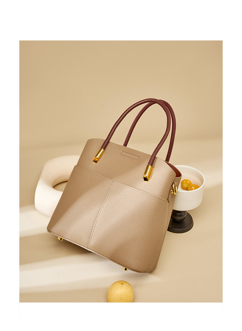 Gray bucket bag styled with a ceramic vessel and yellow plums