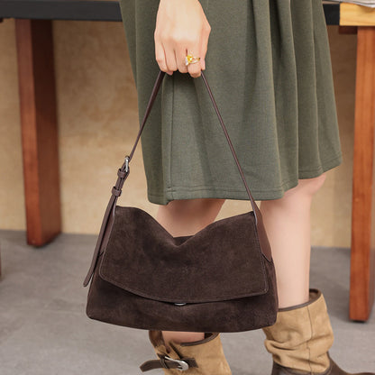 Brown suede leather shoulder bag with flap carried by hand
