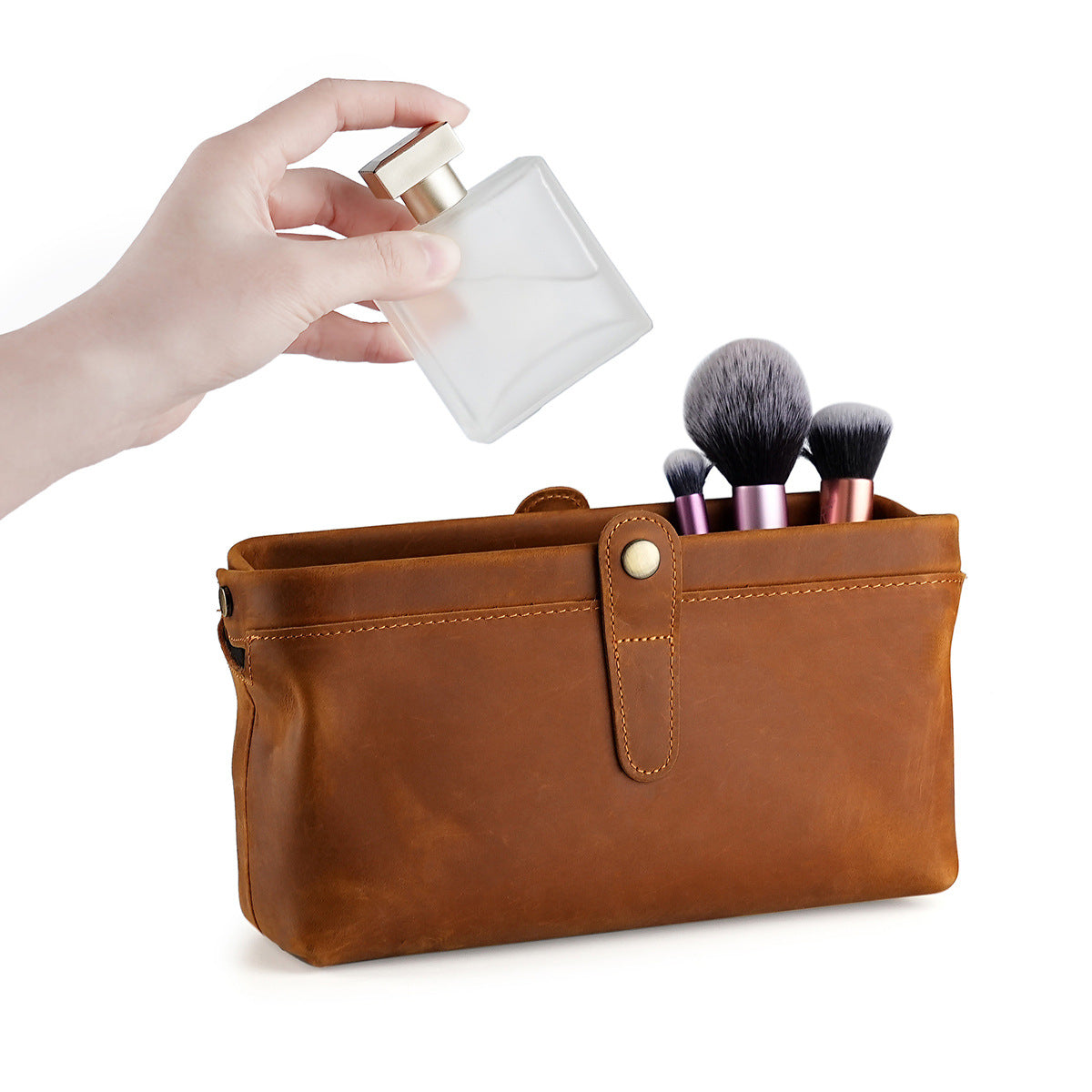 Open brown cosmetic pouch holding makeup brushes and perfume