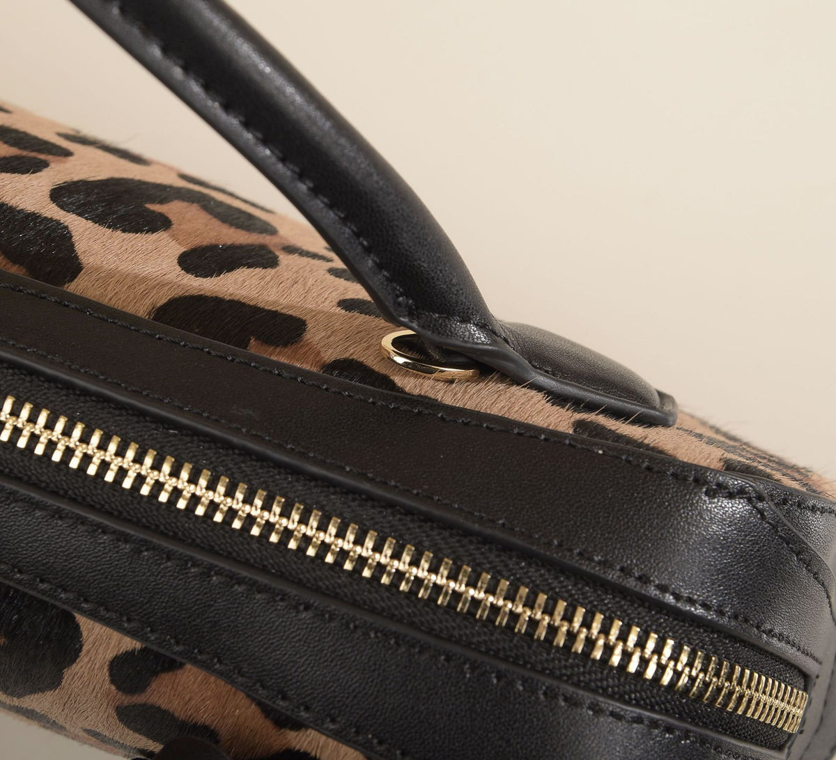 Macro view of the top handle, stitching, and zipper edge