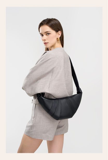 Back view of model with black crescent bag worn as shoulder bag