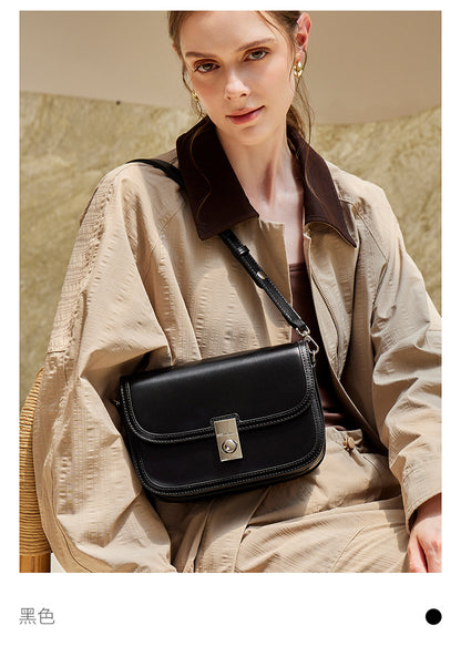 Black leather messenger bag styled with neutral outerwear