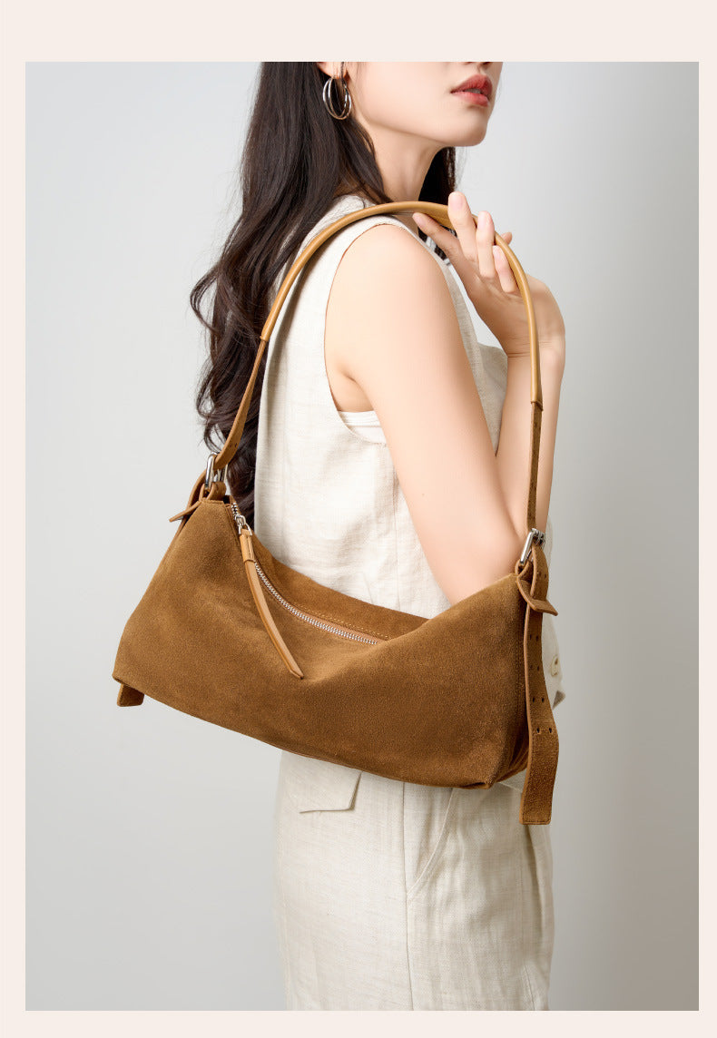 Model holding the caramel suede shoulder bag in front