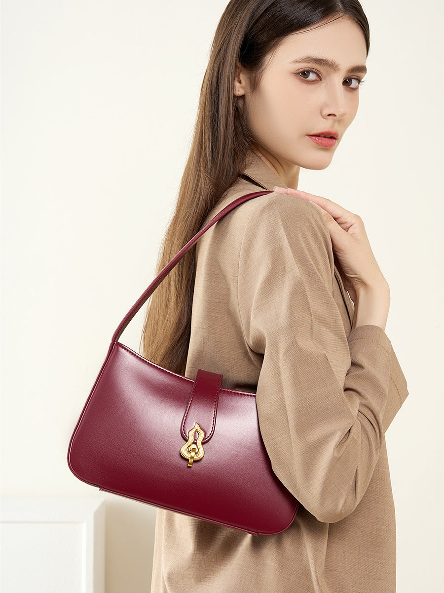 Burgundy leather shoulder bag worn over shoulder with beige blazer