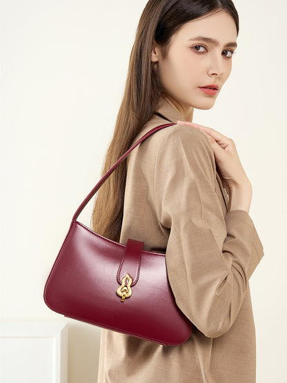 Burgundy leather shoulder bag worn over shoulder with beige blazer