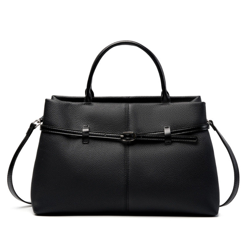 Black pebbled cowhide leather tote bag with top handles and front buckle detail on white background