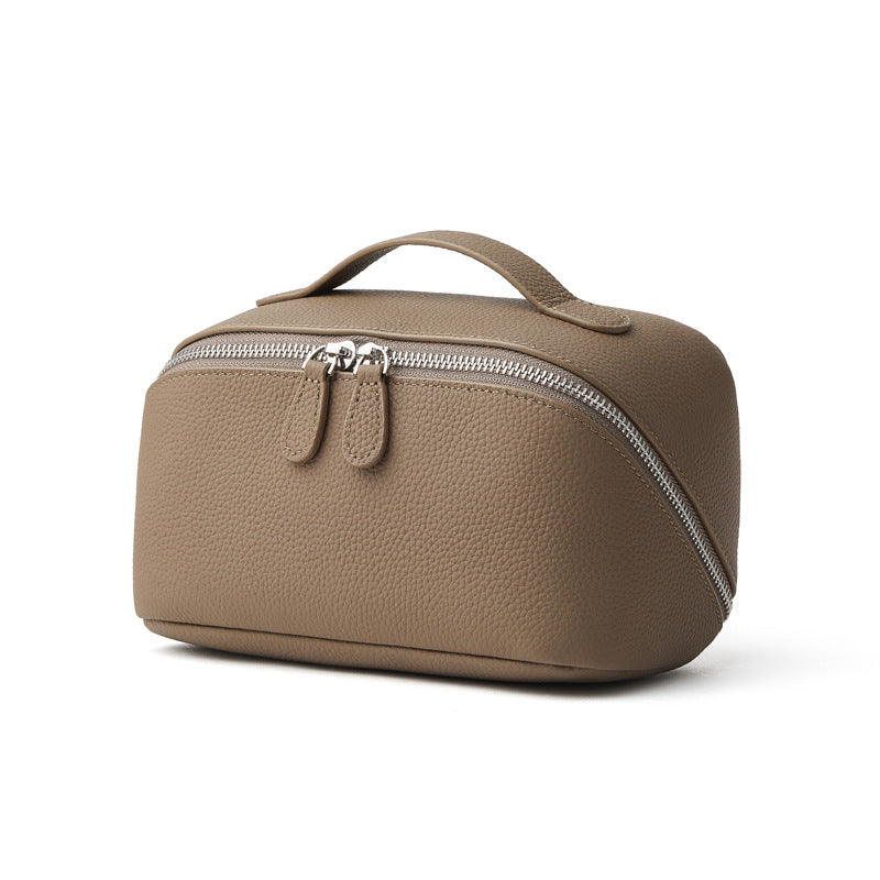 Gray pebbled cowhide leather cosmetic pouch with top handle and silver-tone zipper on white background