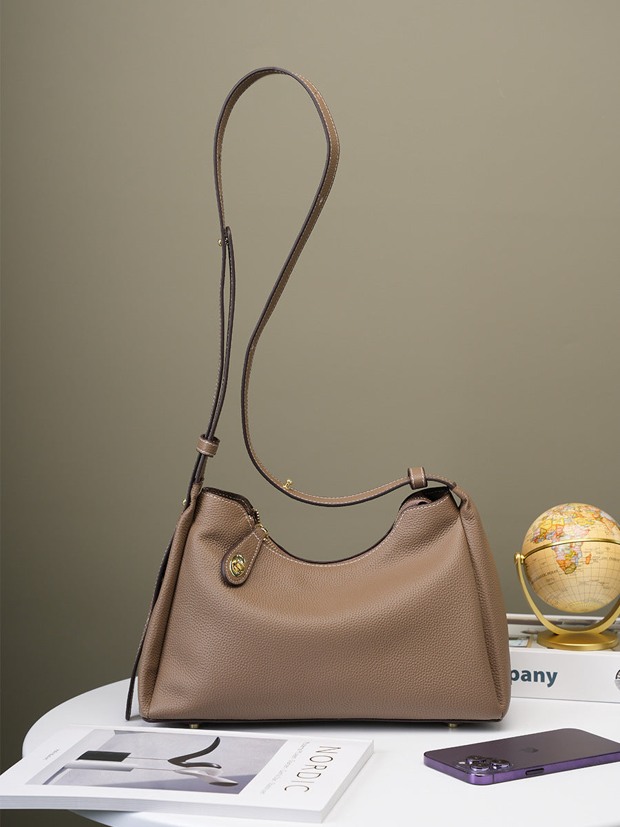 Dark gray leather shoulder bag styled with books and globe on table