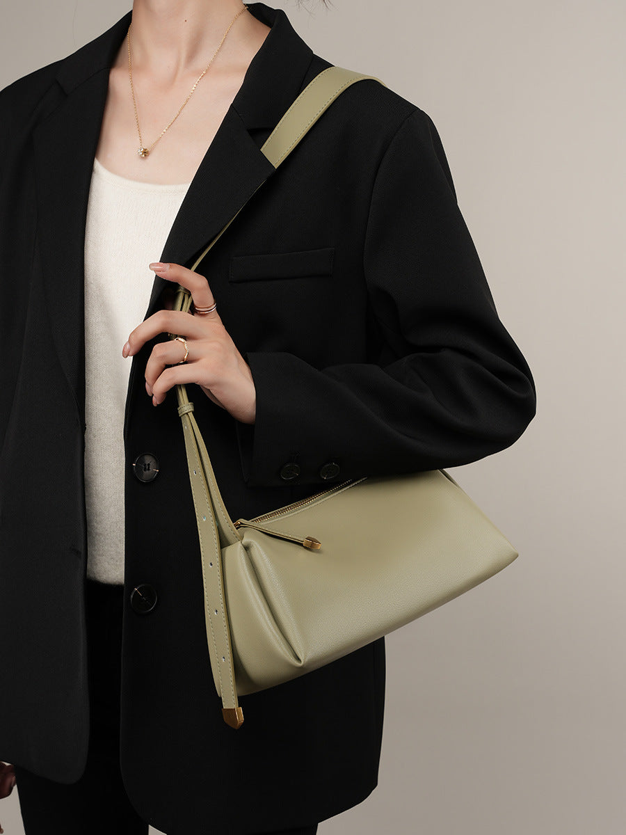 Green pillow crossbody bag worn crossbody with a black blazer