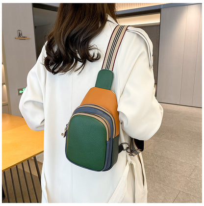 Green and orange sling bag worn with a white coat