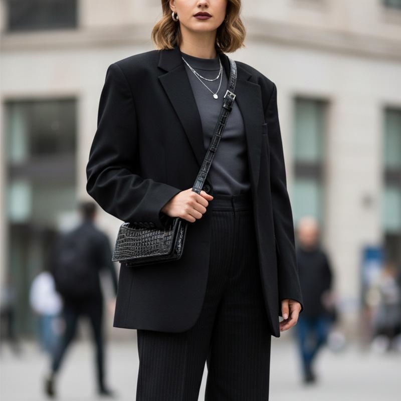Black croc-embossed leather belt bag worn crossbody with a blazer