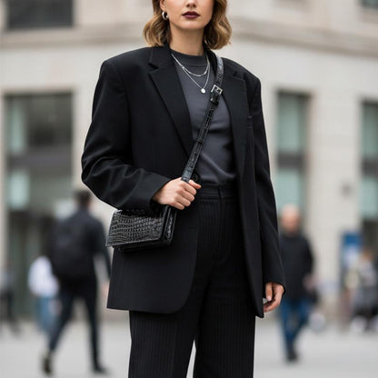 Black croc-embossed leather belt bag worn crossbody with a blazer