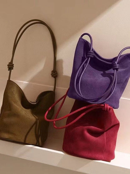 Purple, red, gray, and brown bucket bags displayed on a shelf