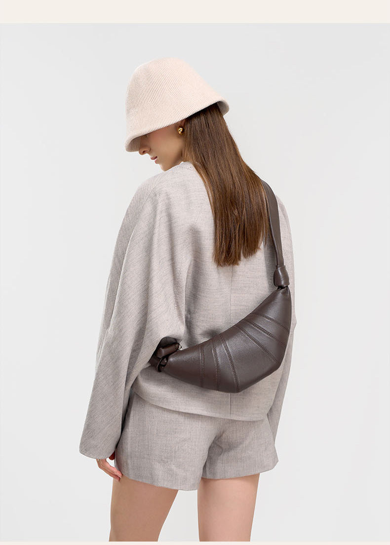 Back view of model in beige hat carrying coffee crescent bag