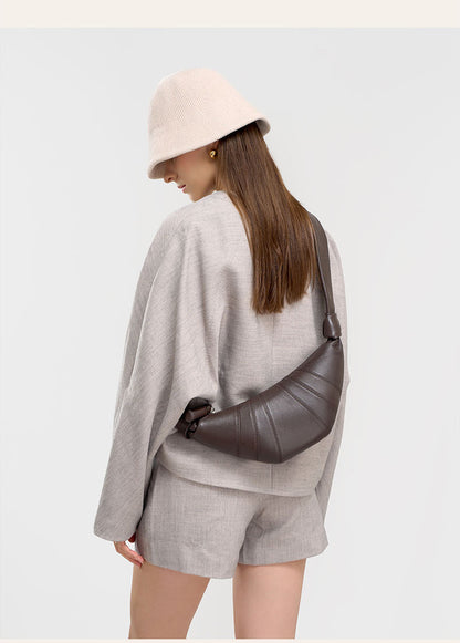 Back view of model in beige hat carrying coffee crescent bag