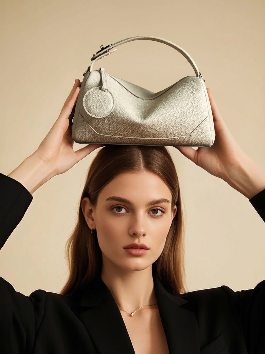 Model balancing ash white mini Boston bag on top of head with black blazer