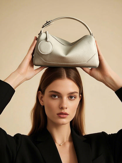 Model balancing ash white mini Boston bag on top of head with black blazer