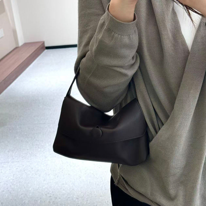 Dark leather mini bag worn over the shoulder with casual outfit