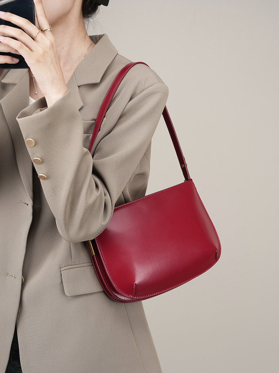 Model wearing a beige blazer carrying the burgundy leather underarm bag on the shoulder