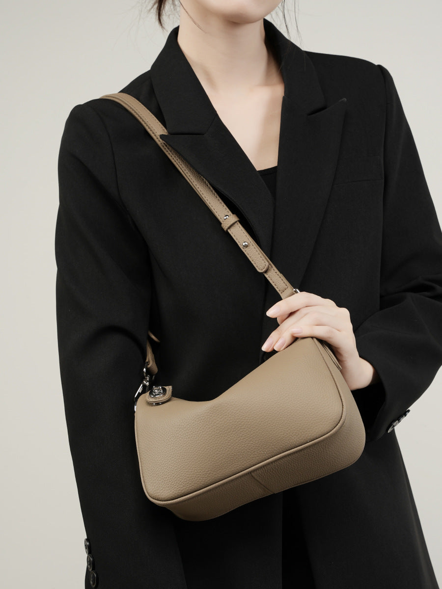Close-up front view of taupe leather crossbody bag on model