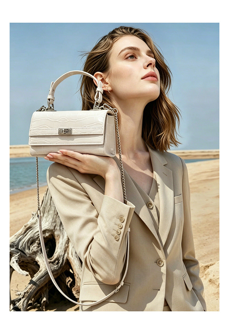 Model resting the cream white croco-embossed bag on her shoulder in a soft outdoor light