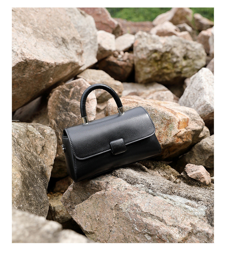 Black cowhide leather mini crossbody bag on natural stone background