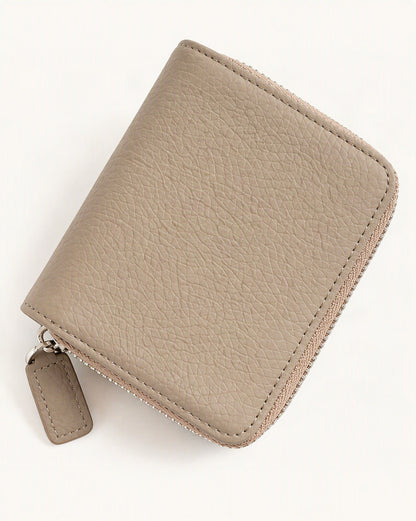 Cowhide Leather Compact Bi-Fold Wallet — front three-quarter view on a warm white background