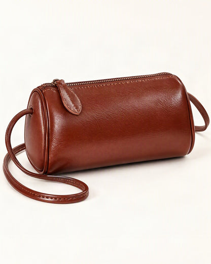 Top-Grain Cowhide Mini Barrel Crossbody Bag — front three-quarter view on a warm white background