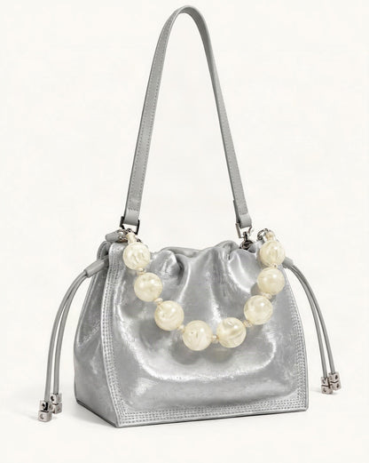 Cowhide Mini Bucket Bag Crossbody Drawstring Bead Handle — front three-quarter view on a warm white background