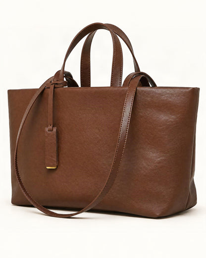 Cowhide Leather Tote Bag with Crossbody Strap — front three-quarter view on a warm white background