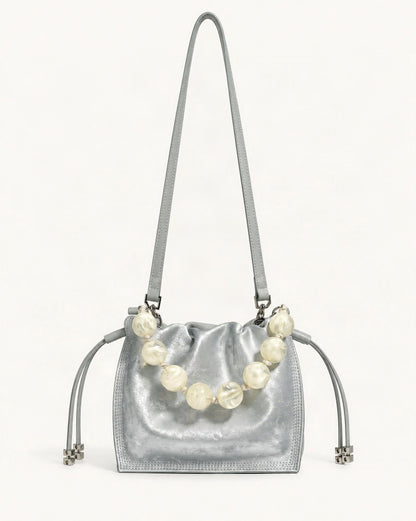Cowhide Mini Bucket Bag Crossbody Drawstring Bead Handle — straight-on front view on a warm white background