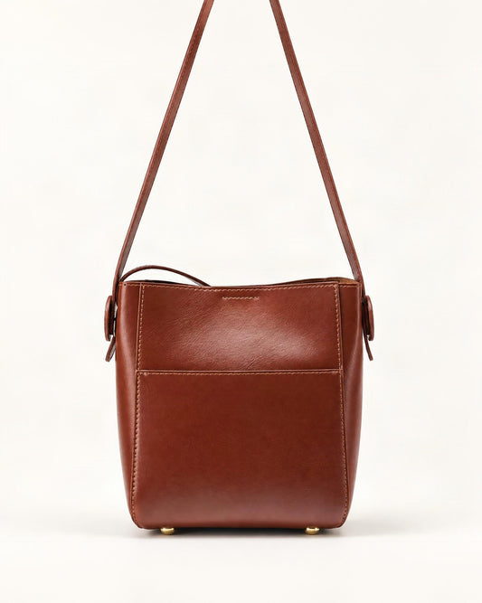 Cowhide Leather Bucket Crossbody Bag — straight-on front view on a warm white background
