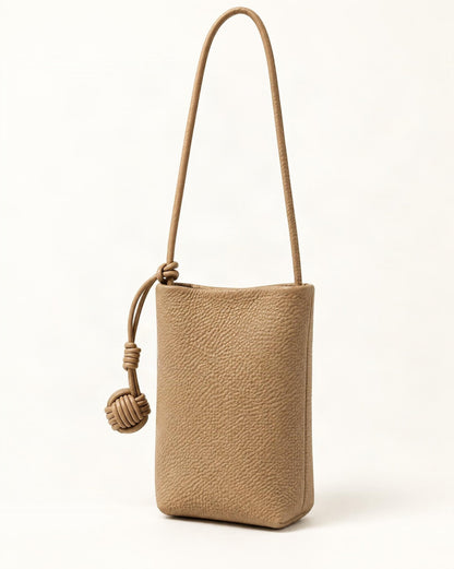 Cowhide Leather Micro Bucket Phone Crossbody Bag — front three-quarter view on a warm white background