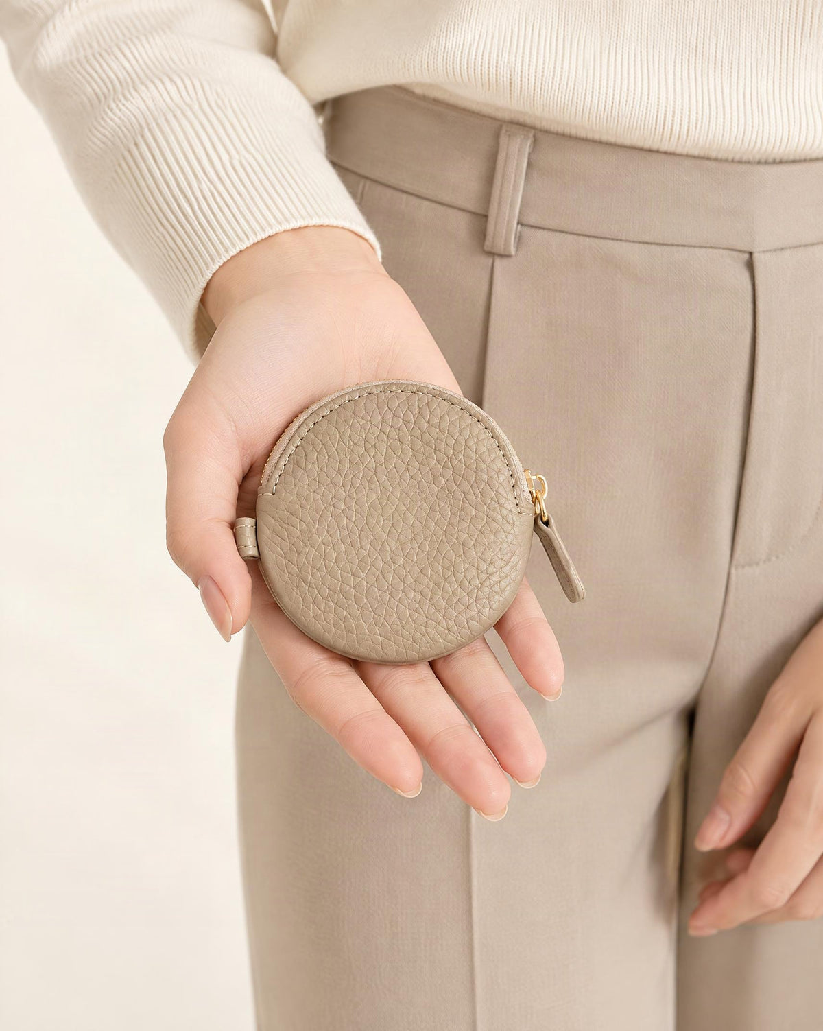 Cowhide Leather Mini Round Zip Pouch held in hand by a model
