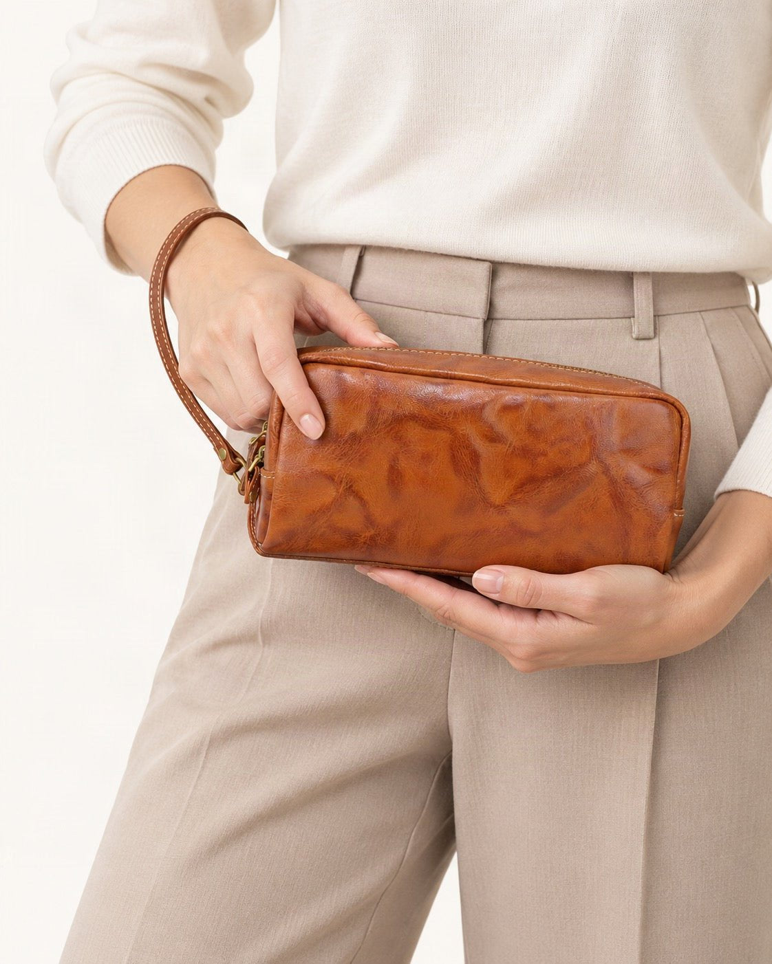 Vegetable-Tanned Leather Cosmetic Wristlet Pouch held in hand by a model
