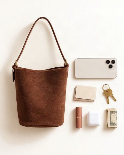 What fits in the Suede Cowhide Bucket Shoulder Bag: a 6.9-inch phone (iPhone 16 Pro Max), cards, keys, a lipstick, AirPods in their case, folded notes