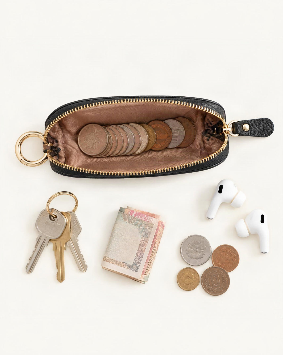 What fits in the Top-Grain Cowhide Mini Zip Pouch with Keyring Clip: keys, coins, a few banknotes folded over into a small stack, no complete flat bill face showing, earbuds